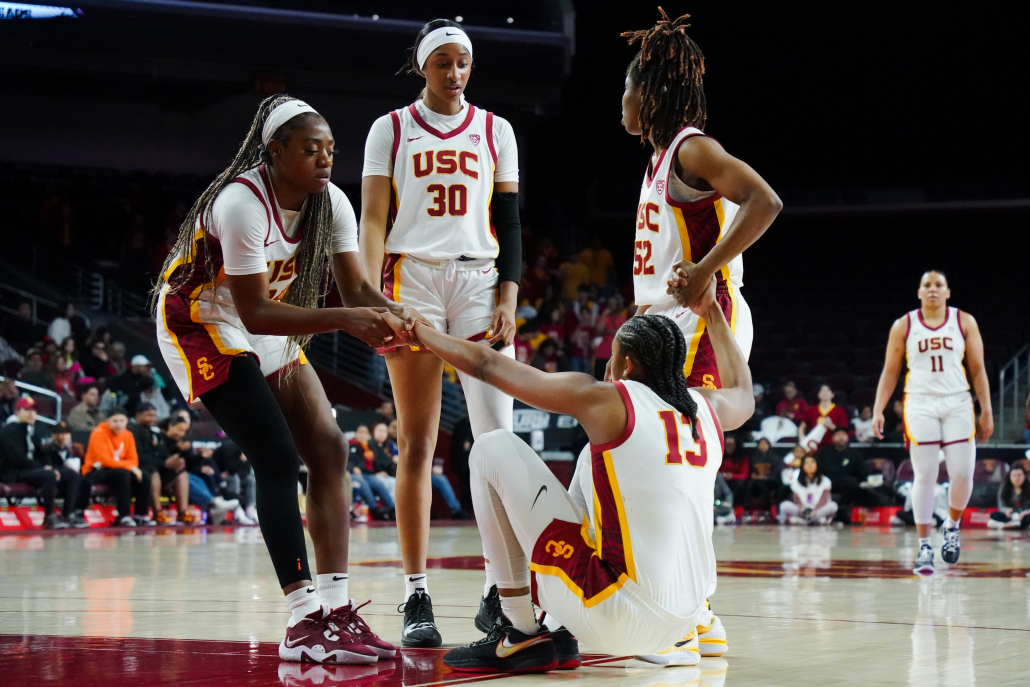 Members of the women's basketball team are helping up a fellow teammate from the ground.