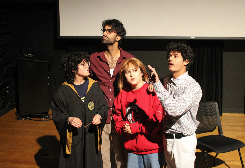 A person in a Harry Potter robe and a person in a red wig standing in front of two people. 