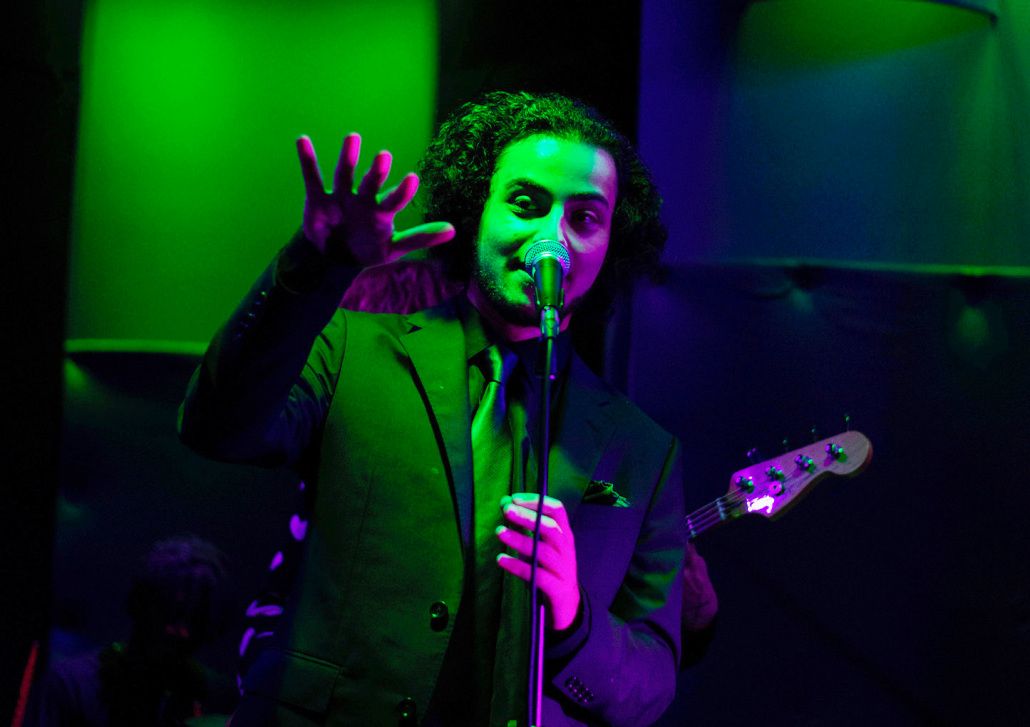 Man singing in green and purple lighting.