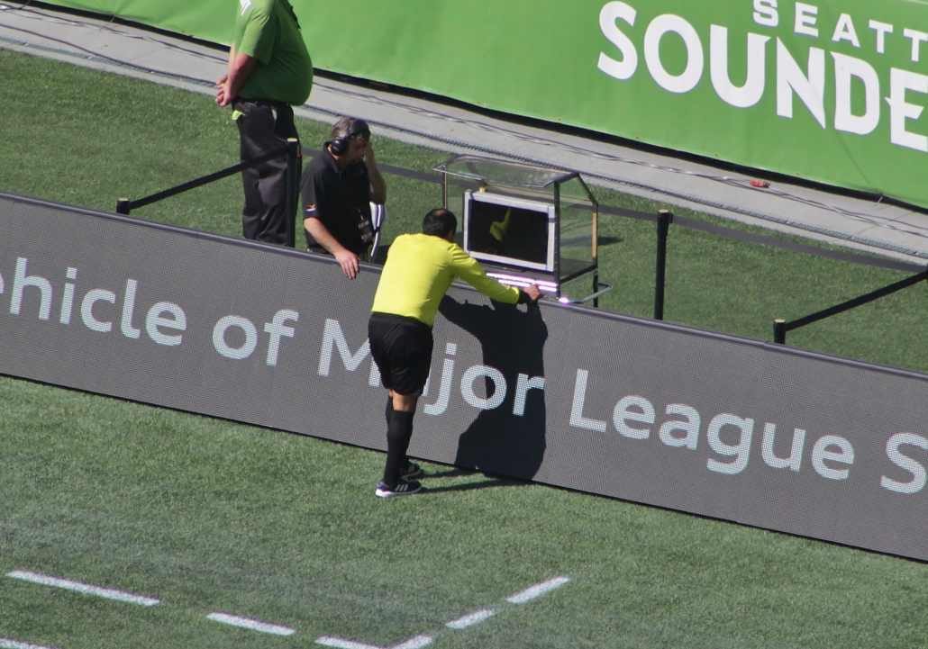Referee leaning over barrier and watching playback
