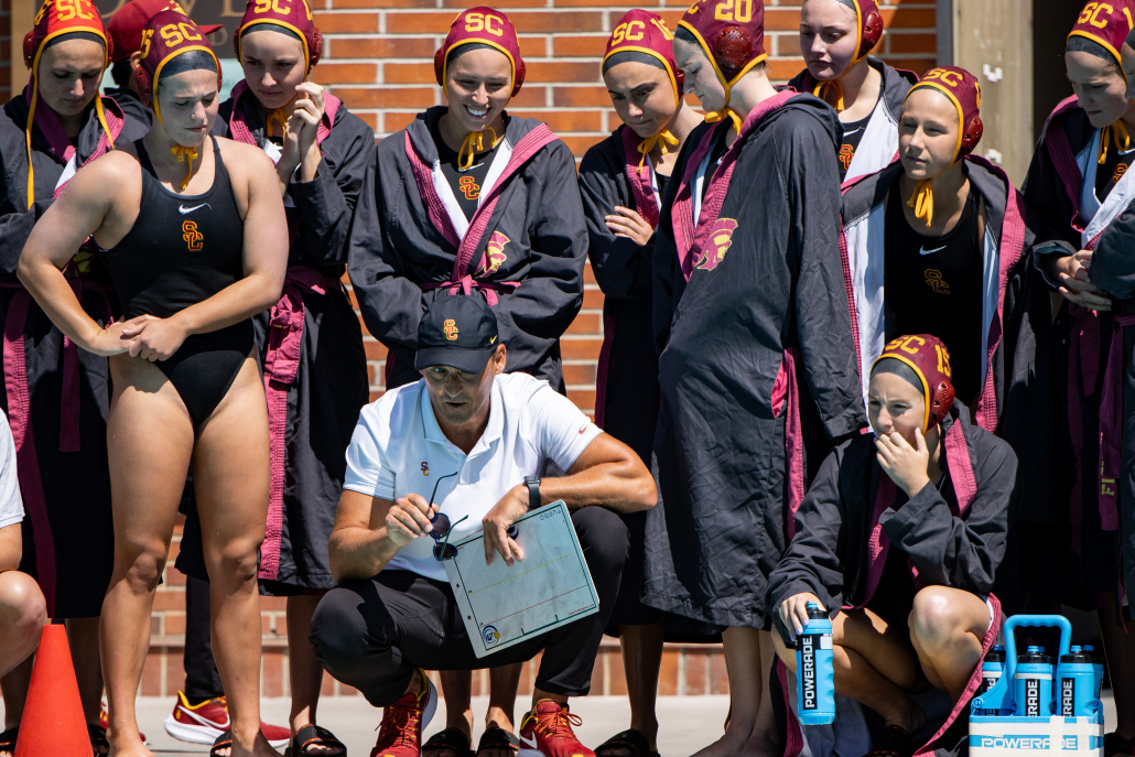 Head Coach Marko Pintaric is hunched down in the center of the entire women's water polo team 