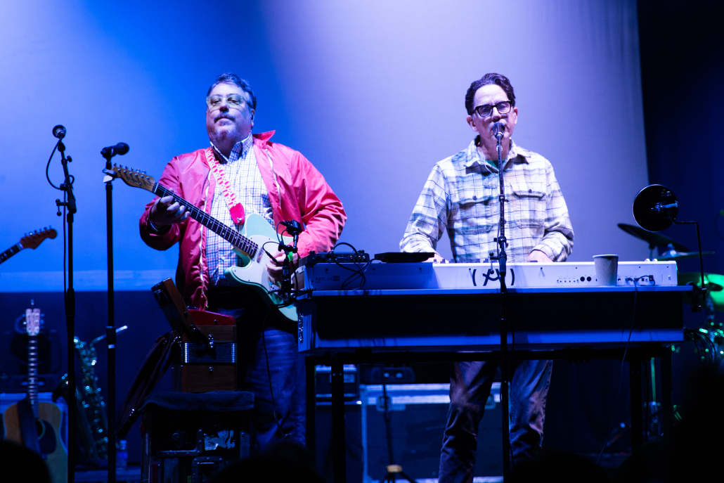 A photo of They Might Be Giants playing instruments on stage.