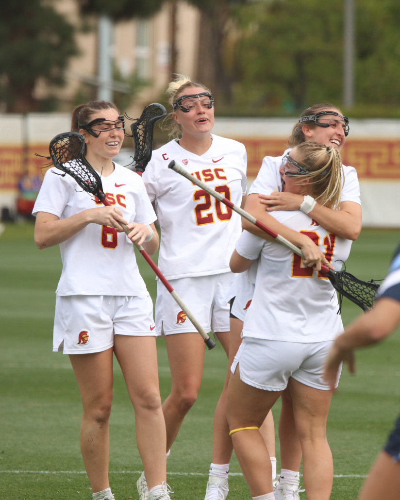The women's lacrosse team watches as two of their teammates embrace for a hug 
