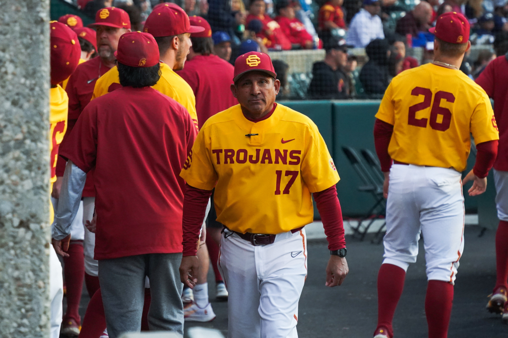 Head Coach of the baseball team wearing gold colored jersey stands in the center 