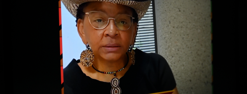 a woman wearing a hat and glasses on a television screen.