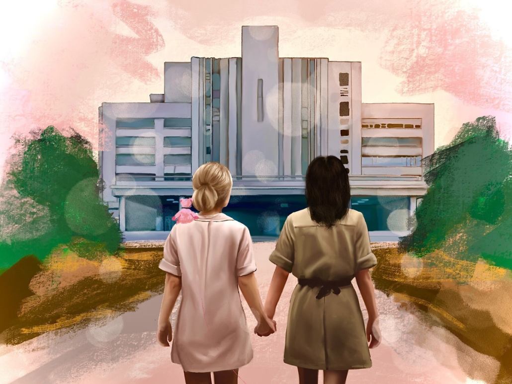 two women standing in front of a hospital, looking at it and holding hands.