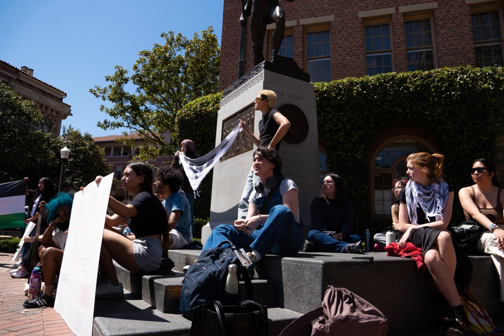 Students sit on Tommy Trojan