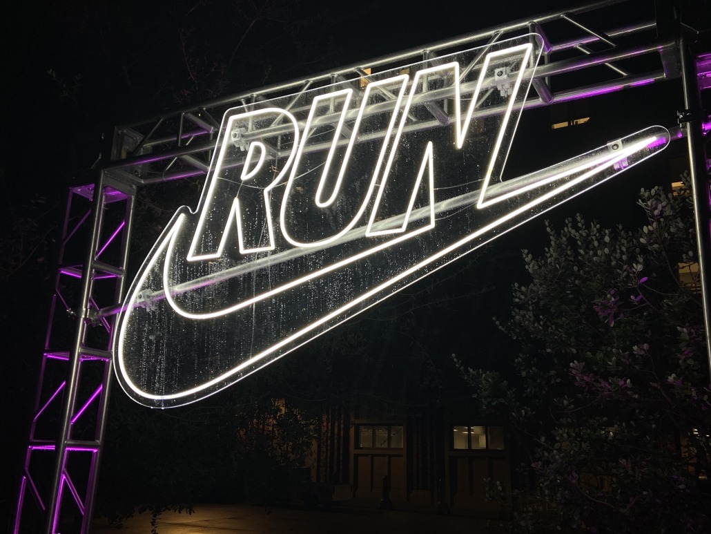 A neon Nike sign illuminating the night at the Nike After Dark tour's stop at USC Village.