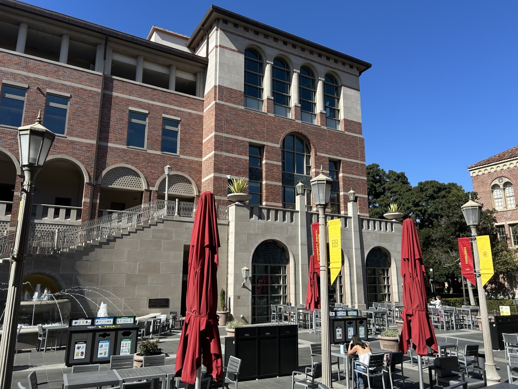 Red and yellow umbrellas partially obscure the outside of The Forum in the Ronald Tutor Campus Center