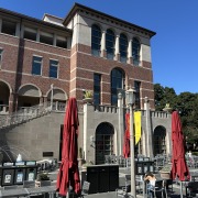 Red and yellow umbrellas partially obscure the outside of The Forum in the Ronald Tutor Campus Center