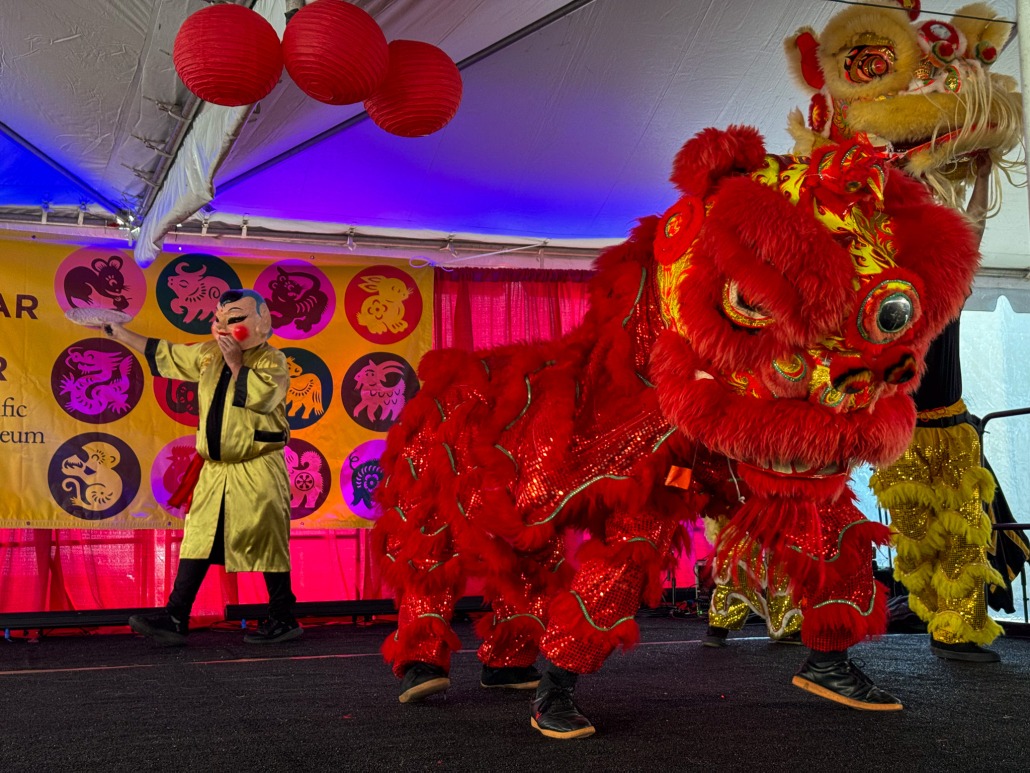 Two large dragons, one yellow and one red, dance atop a stage.