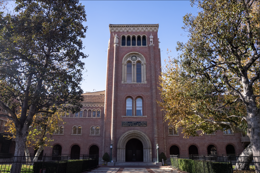 A view of Bovard Auditorium partially covered by trees.