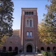 A view of Bovard Auditorium partially covered by trees.