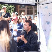 Charlie Kirk sits on a chair and speaks into a microphone.