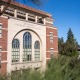 The front of the Engemann Health Center, a red brick building with a cream-colored center. Above the three tall rectangular windows in the cream-colored center of the facade is the text "Engemann Student Health Center."