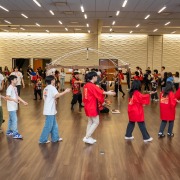 Students dressed in red or white clothing dance in a circle.