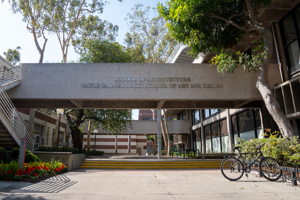 A gray walkway above an open courtyard. On the side of the walkway is the text "School of Architecture" on the upper line and "Gayle Garner Roski School of Art and Design" on the lower line.