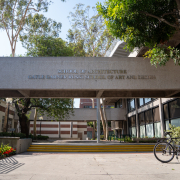 A gray walkway above an open courtyard. On the side of the walkway is the text "School of Architecture" on the upper line and "Gayle Garner Roski School of Art and Design" on the lower line.