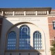 Upward-facing view of the facade of Engemann Student Health Center, with the title of the building engraved in the cream-colored wall of the building above three arcing windows.