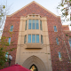The facade of Fertitta Hall, a brick building with a stone column in the center and a triangular brick roof.