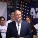 Doug Emhoff stands behind a podium at a Biden-Harris event with supporters behind him.