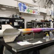 A rocket created by the Rocket Propulsion Lab named Malibu sits in their lab with signed names on its wings.