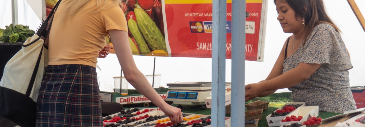 Student shops at fruit stand at the Trojan Farmers Market.
