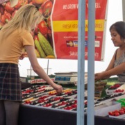 Student shops at fruit stand at the Trojan Farmers Market.