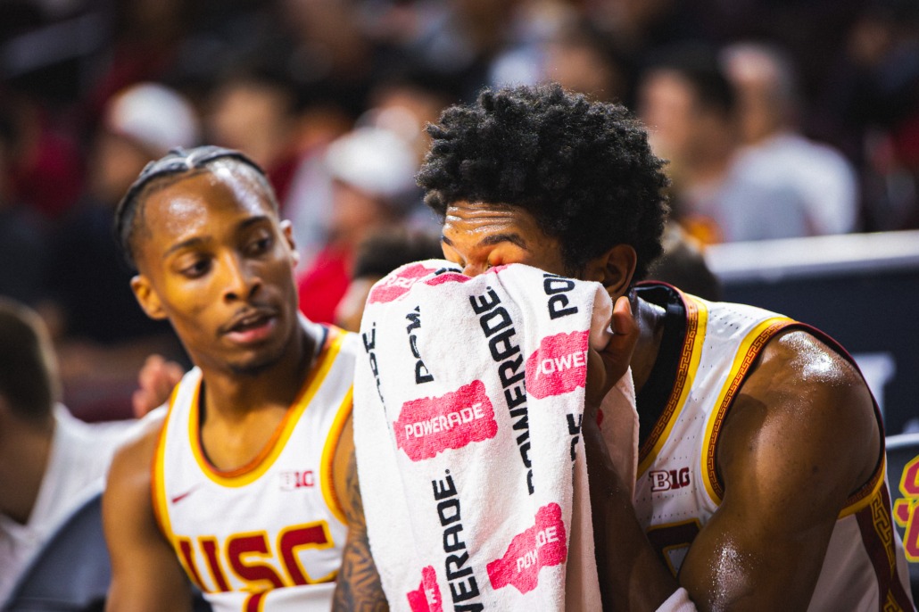 USC men's basketball players sit on the bench during a game