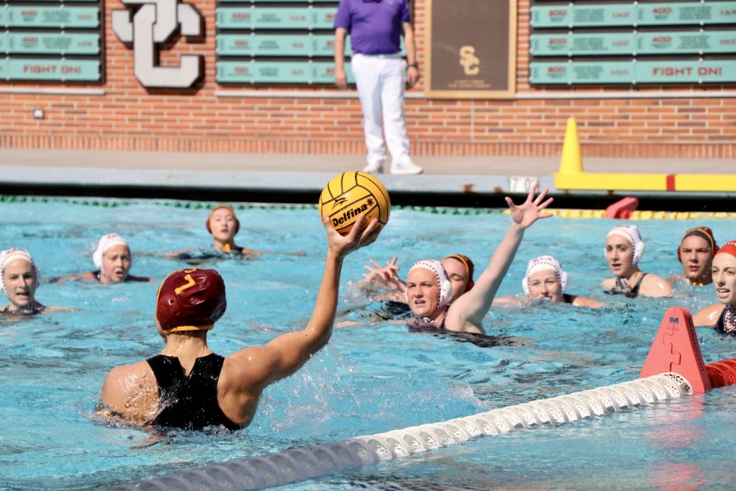 A women's water polo player looks for a teammate to pass to