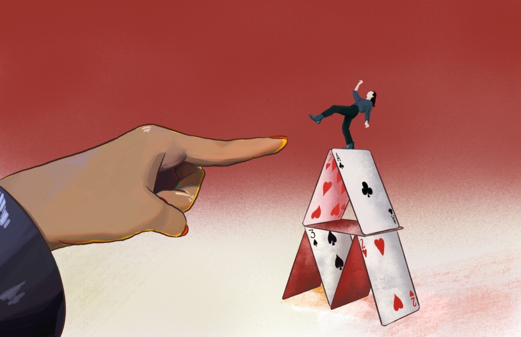 A finger about to push over a woman on a house of cards