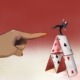 A finger about to push over a woman on a house of cards
