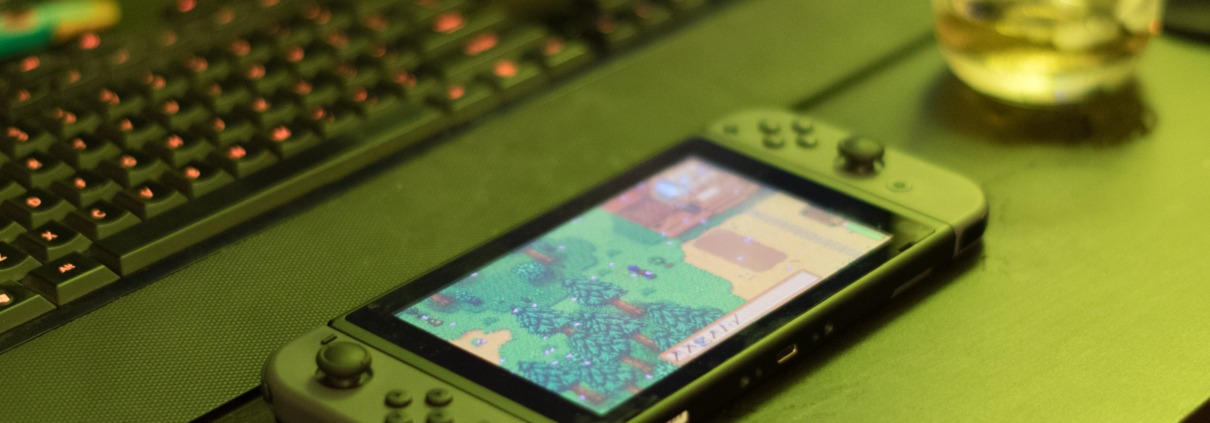A green Nintendo Switch with Stardew Valley playing sits on a green table.