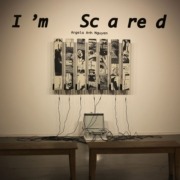 Seven strips of black-and-white rug hung on a wall. Wires connect the bottom of the strips to a gray briefcase