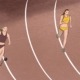 Two women racing on a racetrack, one of them has a weight attached to her leg