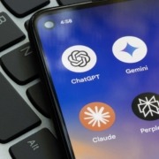 A phone with multiple AI apps laying on a keyboard.