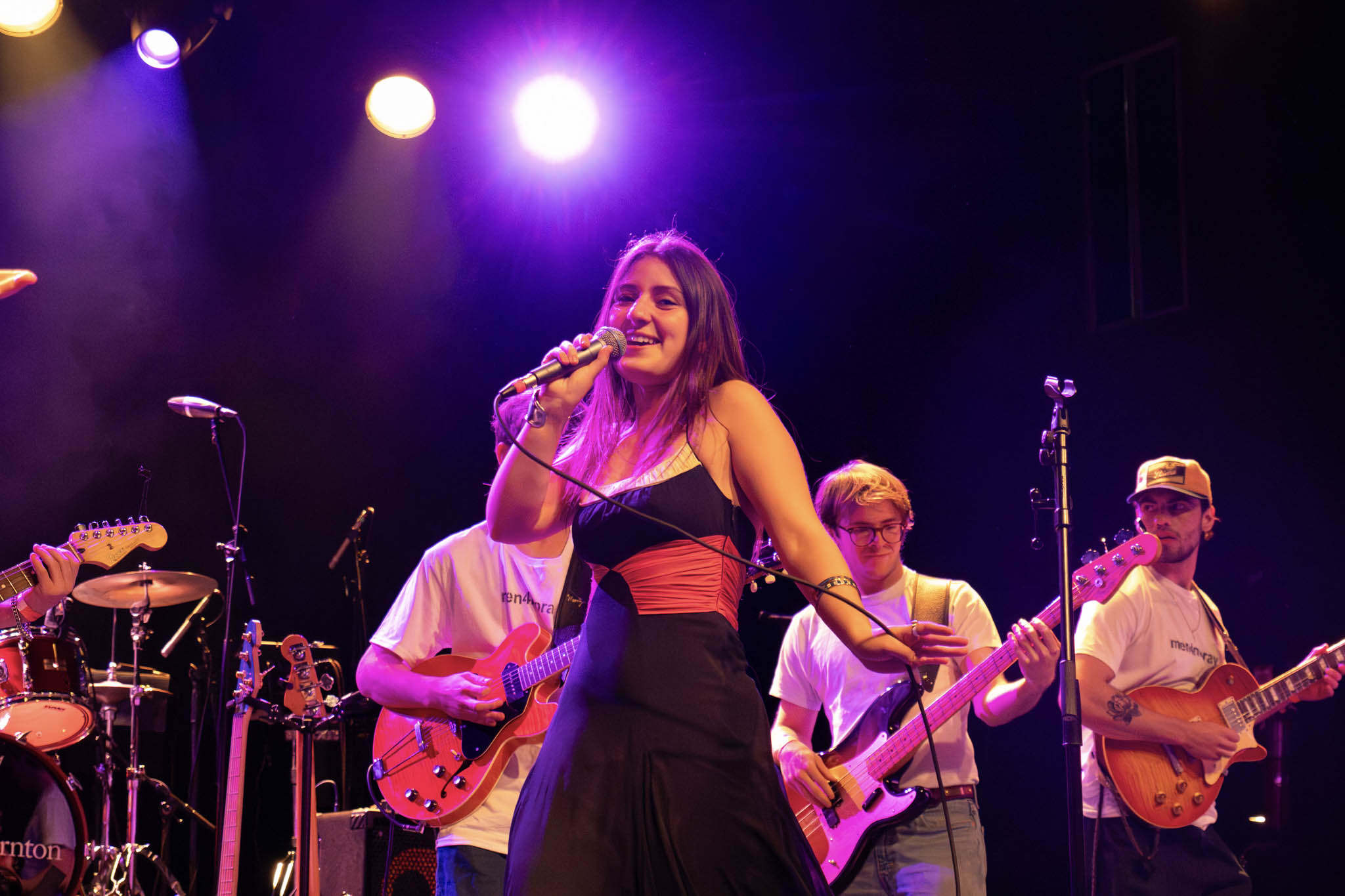 A girl sings on stage at the pop showcase with a backing behind her.