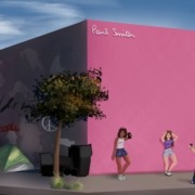 Three people doing a photoshoot at the famous L.A. pink wall while the other side of the wall features homelessness and graffiti .