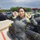 student founder sprays her skincare on her face in front of her racecar