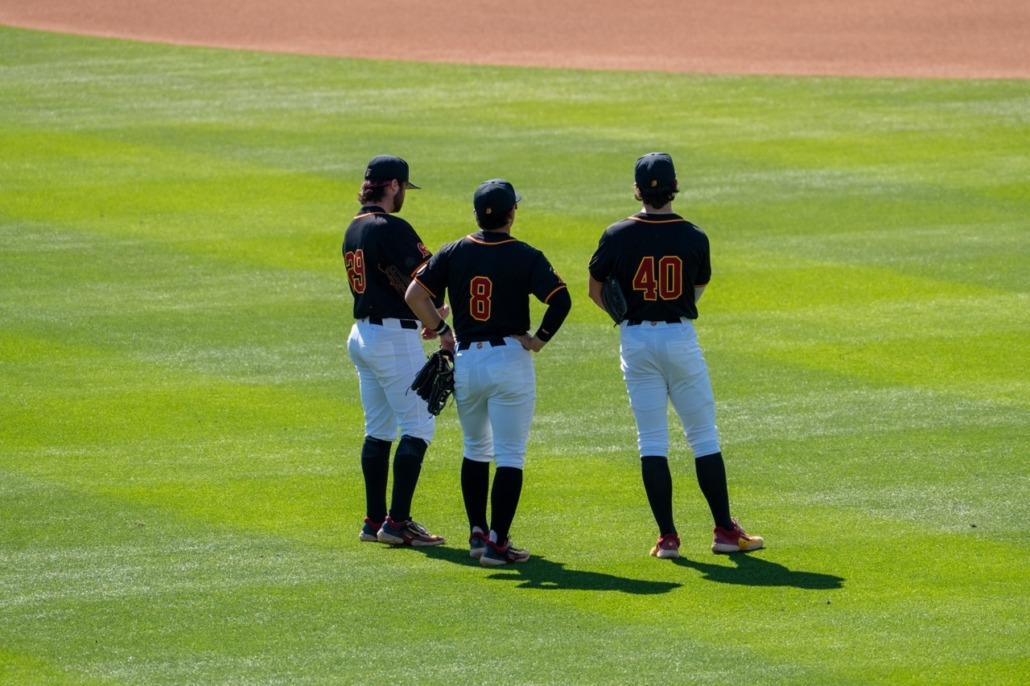 Three USC players stand together in the outfield