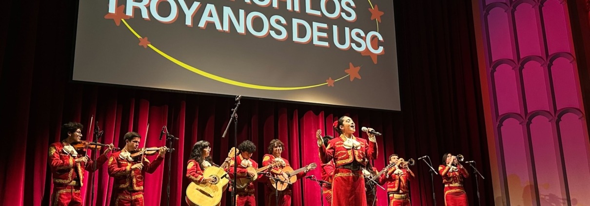 Mariachi Los Troyanos de USC perform on stage at Bovard Auditorium, dressed in all red outfits.