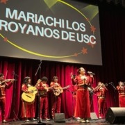 Mariachi Los Troyanos de USC perform on stage at Bovard Auditorium, dressed in all red outfits.