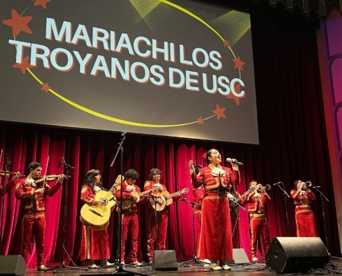 Mariachi Los Troyanos de USC perform on stage at Bovard Auditorium, dressed in all red outfits.