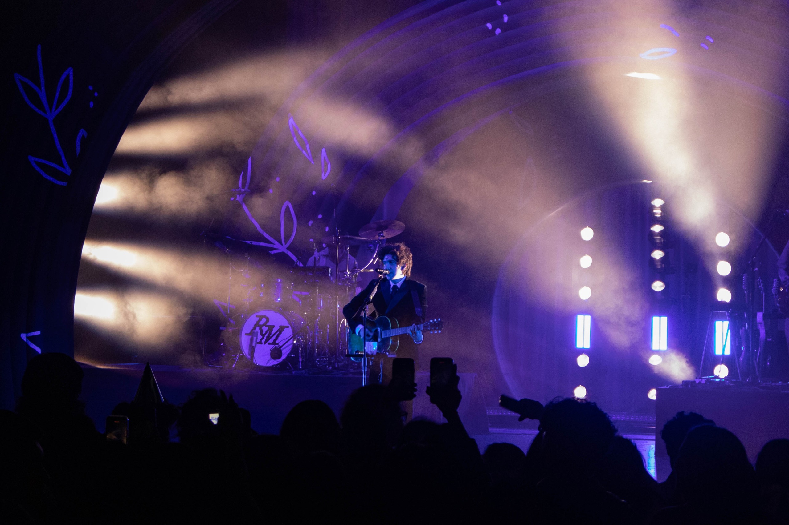 Ricky Montgomery singing while playing guitar in front of fans.