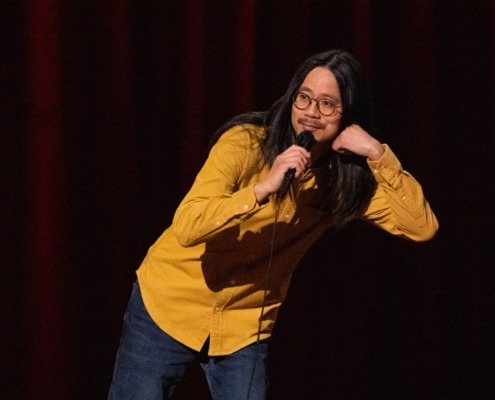 Sheng Wang performs on stage microphone in hand.