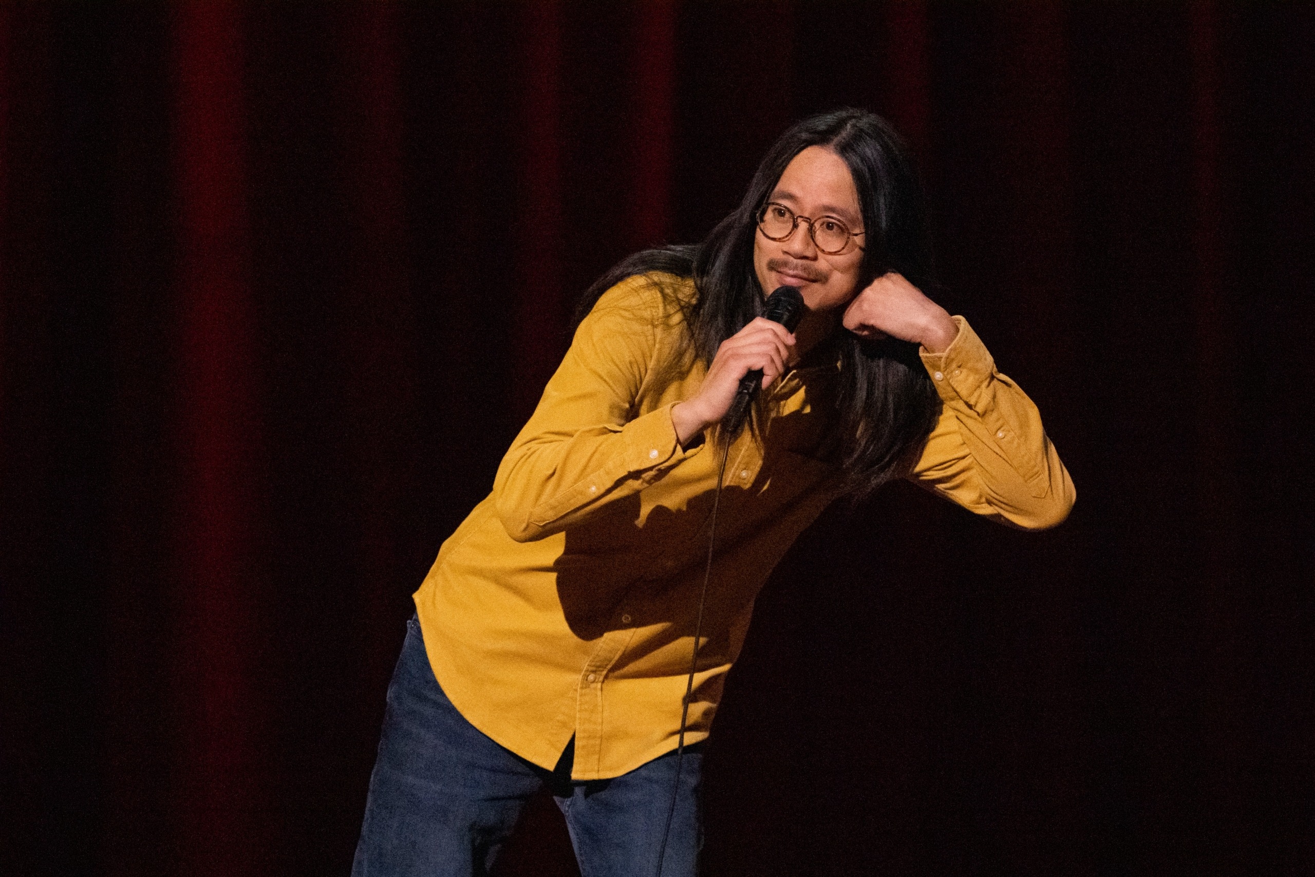 Sheng Wang performs on stage microphone in hand.