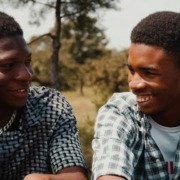 Two men smiling and talking to each other.