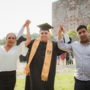 A man graduating school holding hands with his mother and father.