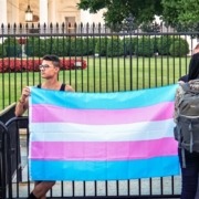 people holding the Transgender pride flag in front of the U.S White House