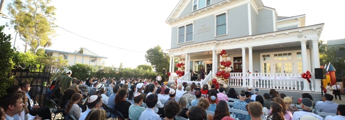people sit outside chabad house opening